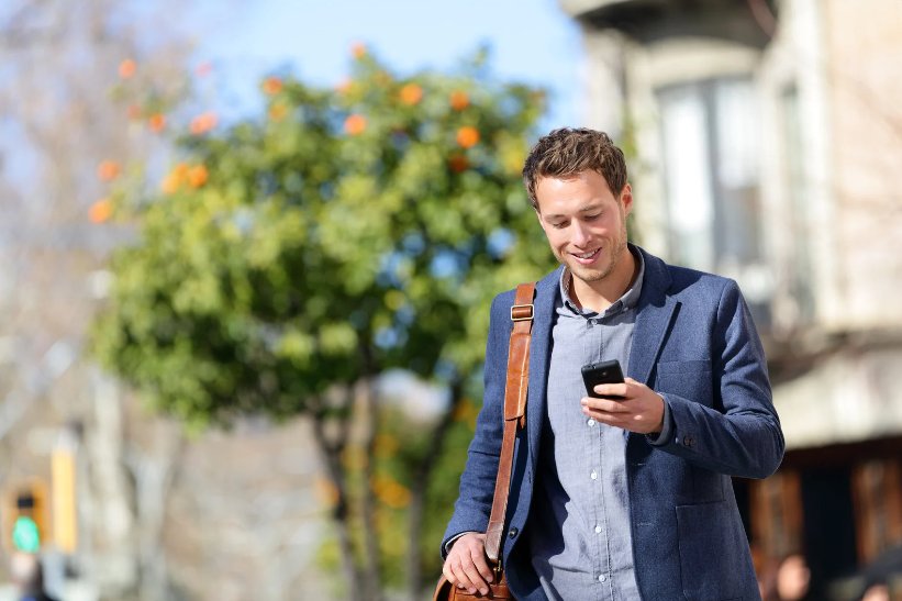 A man using the accessibility features on his phone as he walks to work