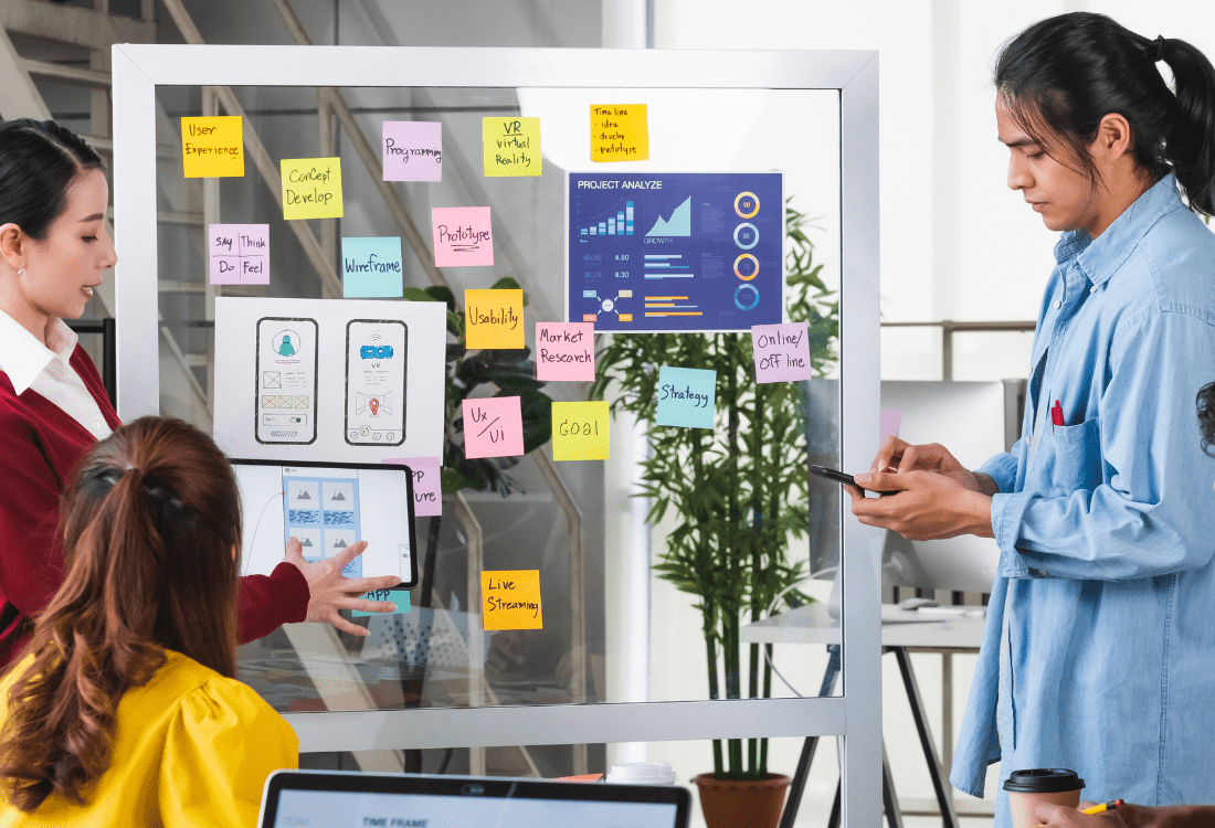 A group of colleagues going through ideas on a board about key promotion strategies for their app.